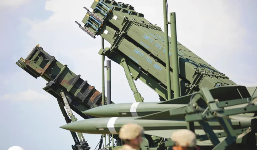 two Patriot missile defence batteries together next to two soldiers