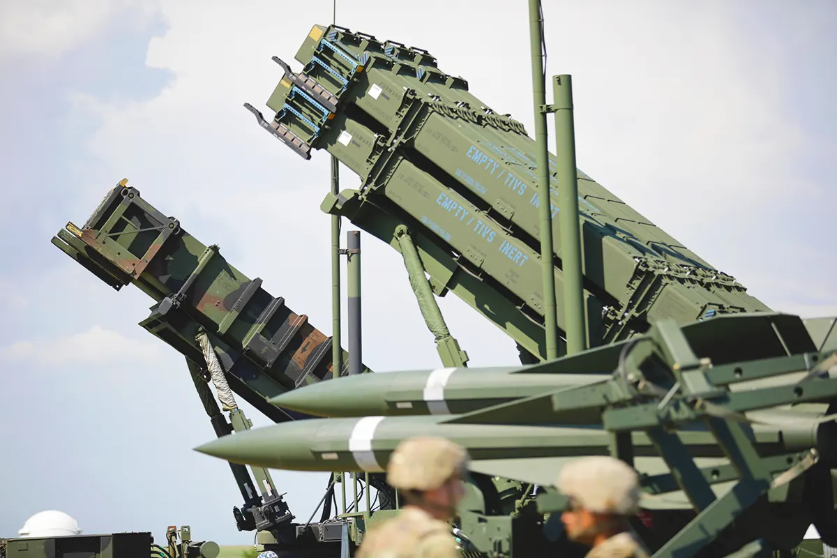 two Patriot missile defence batteries together next to two soldiers
