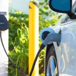 un coche eléctrico de color blanco conectado a un cargador en la calle