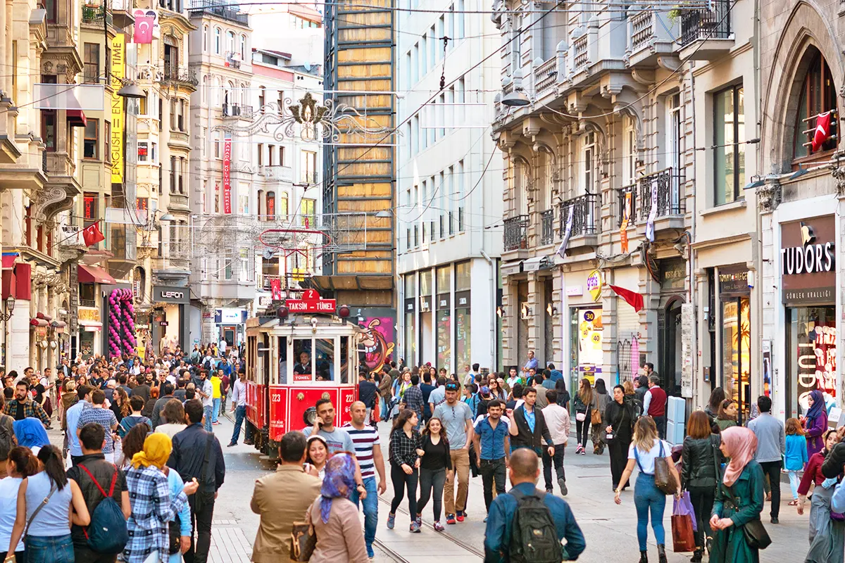 una imagen de la Avenida Istiklal de Estambul con cientos de personas caminando por ella y un tradicional tranvía atravesándola