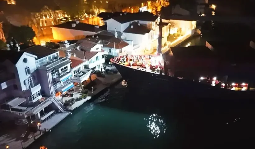 A night-time view of a cargo ship with its bow just a few metres from a mansion on the banks of the Bosphorus