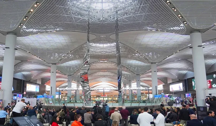imagen de una escultura gigante compuesta por dos piezas metálicas verticales rodeada de gente en el interior del Aeropuerto de Estambul