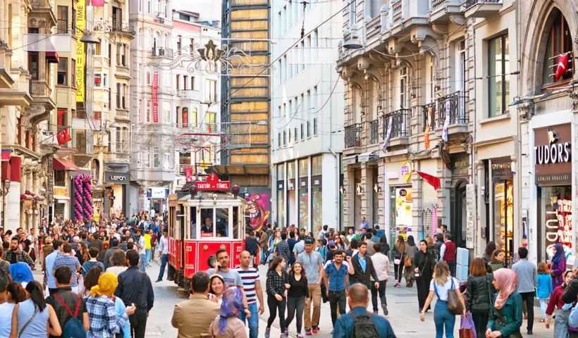 a picture of Istiklal Avenue in Istanbul, with hundreds of people walking along it and a traditional tram crossing it