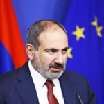 Armenian Prime Minister Nikol Pashinyan, standing next to the flags of Armenia and the EU