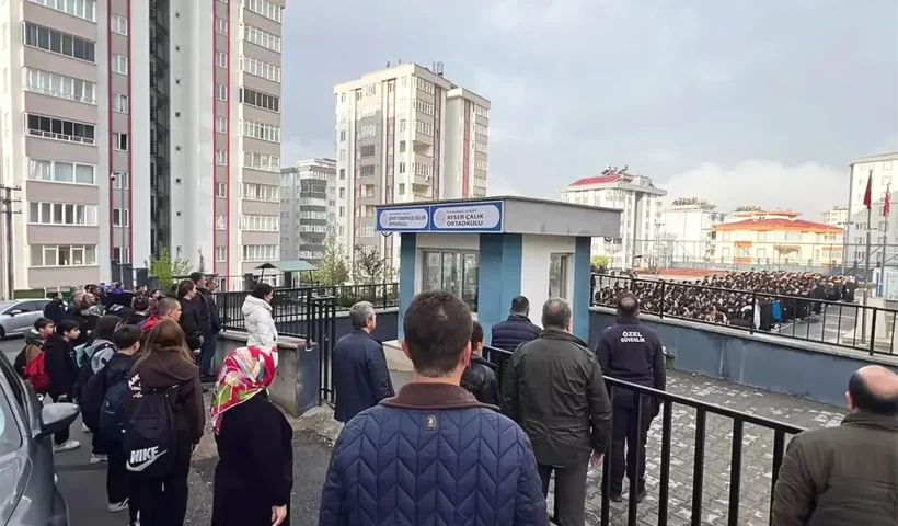 Parents watch from outside the schoolyard where students from the Şehit Tebernuş School in Kahramanmaraş have gathered following the resumption of classes after the shooting