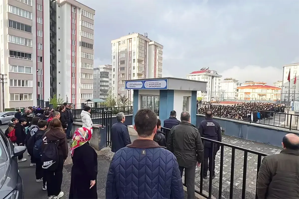 Parents watch from outside the schoolyard where students from the Şehit Tebernuş School in Kahramanmaraş have gathered following the resumption of classes after the shooting