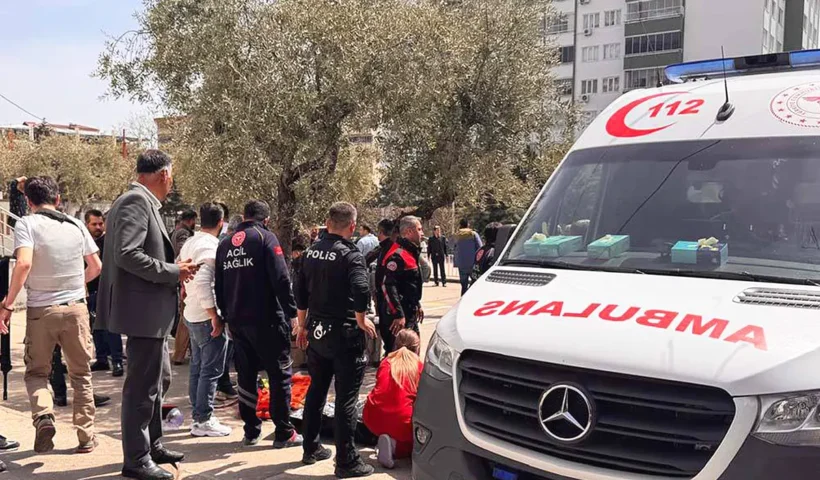Several people standing next to an ambulance and a victim lying on the ground outside a school in Turkey