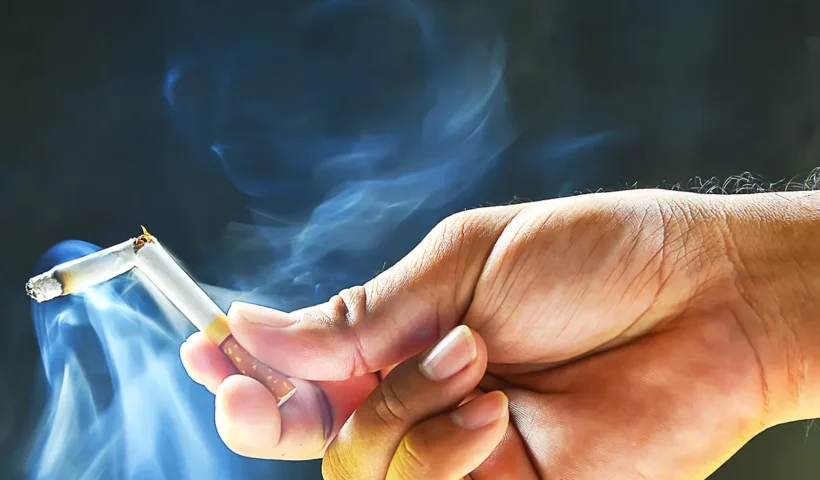 a hand is holding a smoking cigarette broken in half