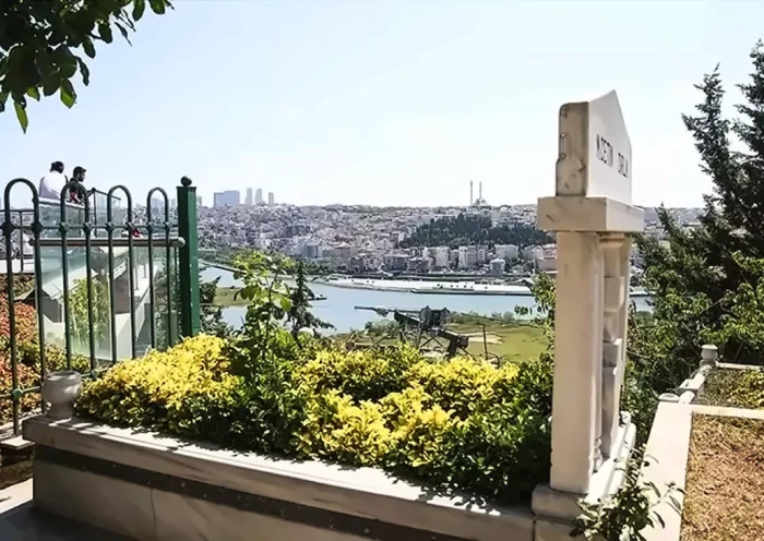 a Muslim grave in a cemetery surrounded by greenery, with a view of Istanbul’s skyline in the background