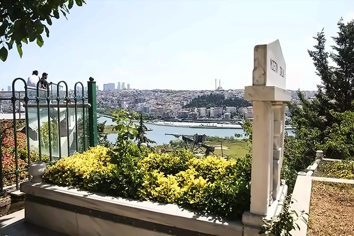 una tumba musulmana en un cementerio rodeado de vegetación con una vista sobre los edificios de Estambul al fondo
