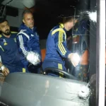 varios jugadores del Fenerbahçe se suben a un autobús en cuyo parabrisas delantero se observan varios impactos de bala
