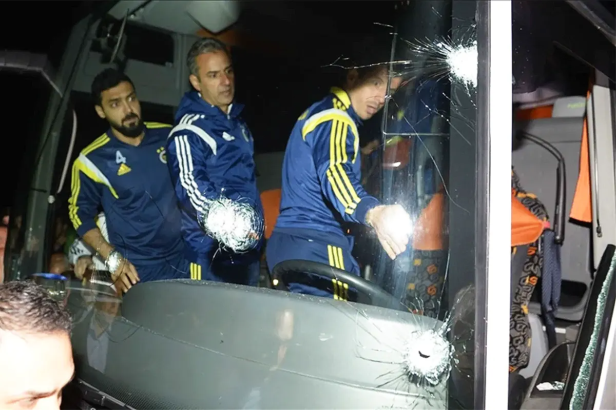varios jugadores del Fenerbahçe se suben a un autobús en cuyo parabrisas delantero se observan varios impactos de bala