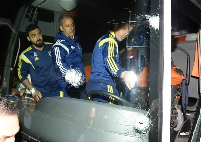 Several Fenerbahçe players board a bus with several bullet holes visible in the windscreen.