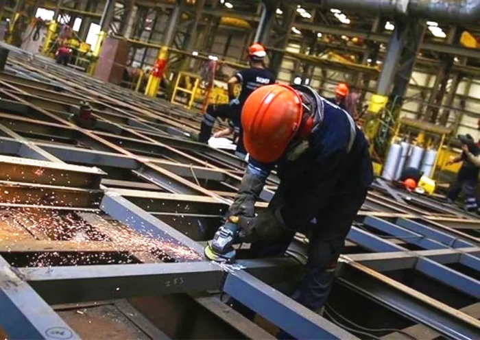 construction workers operating cutting machinery on a metal structure
