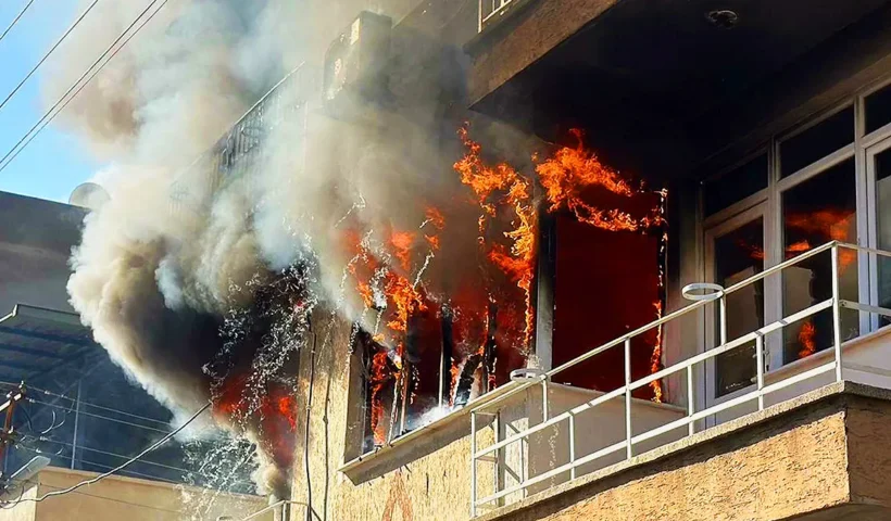 Flames are billowing from the windows and balcony of a house where a fire has broken out