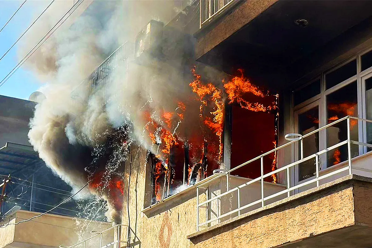 Flames are billowing from the windows and balcony of a house where a fire has broken out