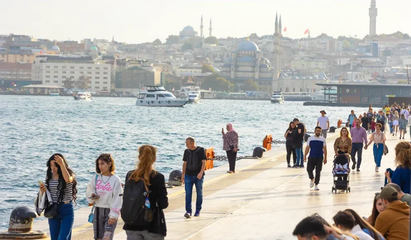 gente paseando junto al mar en el estuario del Cuerno de Oro de Estambul, con varios edificios históricos y mezquitas al fondo
