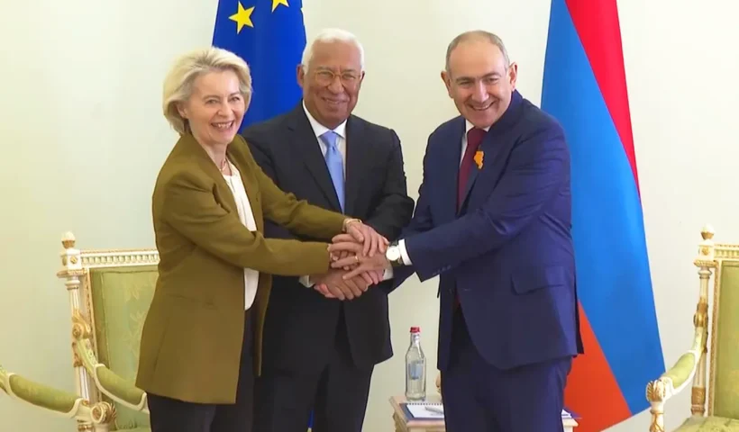 El primer ministro armenio Pashinyan estrecha sus manos con António Costa y Ursula von der Leyen junto a una bandera de la UE y de Armenia.