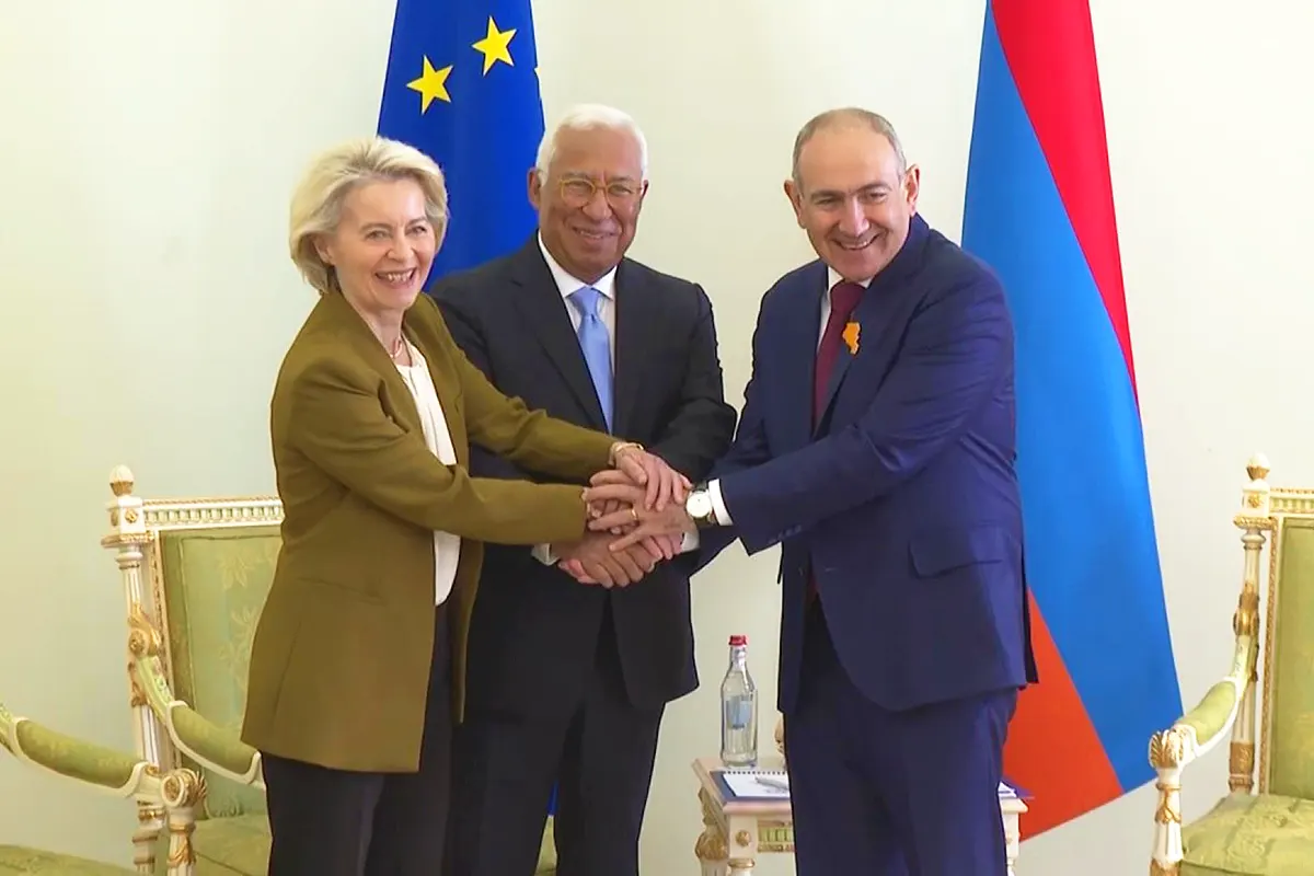 El primer ministro armenio Pashinyan estrecha sus manos con António Costa y Ursula von der Leyen junto a una bandera de la UE y de Armenia.