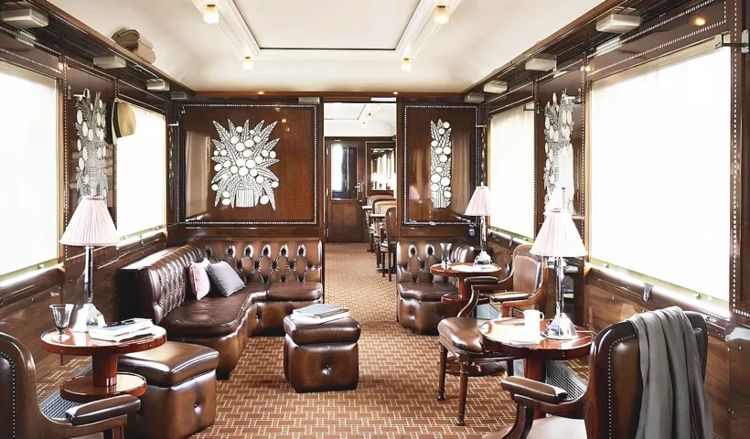 the interior of an Orient Express carriage, showing a lounge luxuriously decorated with wooden furniture, glass ornaments and leather armchairs