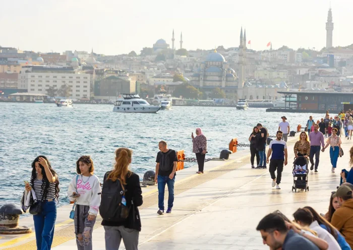 People strolling along the waterfront at Istanbul’s Golden Horn estuary, with several historic buildings and mosques in the background