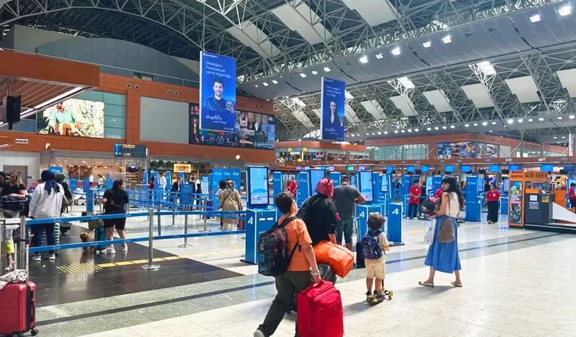 Several passengers are walking with their luggage inside the Sabiha Gökçen Airport terminal in Istanbul