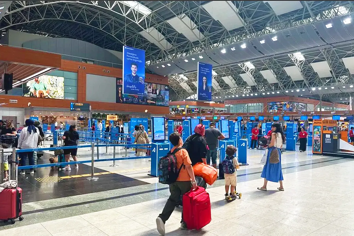 Several passengers are walking with their luggage inside the Sabiha Gökçen Airport terminal in Istanbul