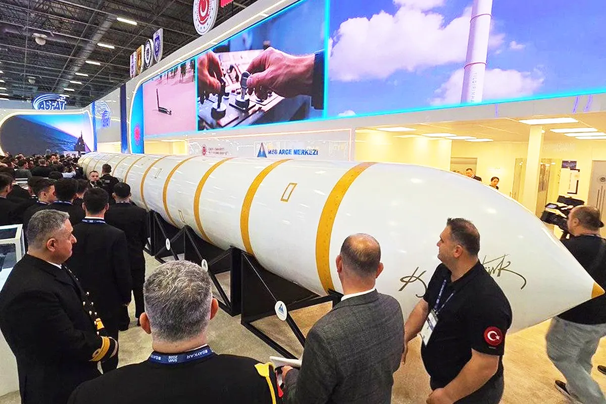 A huge ballistic missile, positioned horizontally, is on display at a crowded exhibition attended by members of the military.