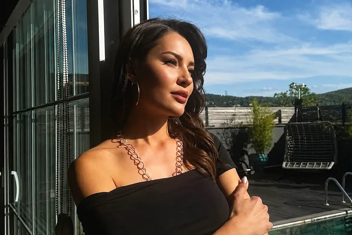 una imagen de la actriz de series turcas Ece İrtem, apoyada al sol contra una puerta vistiendo un vestido negro