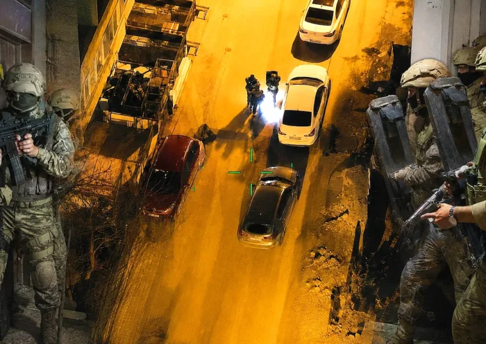 A nighttime aerial shot taken by a drone showing several armed police officers advancing down a street; on either side, members of the Turkish police and gendarmerie special forces