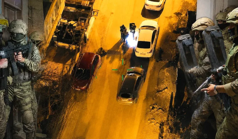 A nighttime aerial shot taken by a drone showing several armed police officers advancing down a street; on either side, members of the Turkish police and gendarmerie special forces