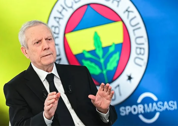 Aziz Yıldırım con traje y corbata con un enorme escudo del Fenerbahçe de fondo