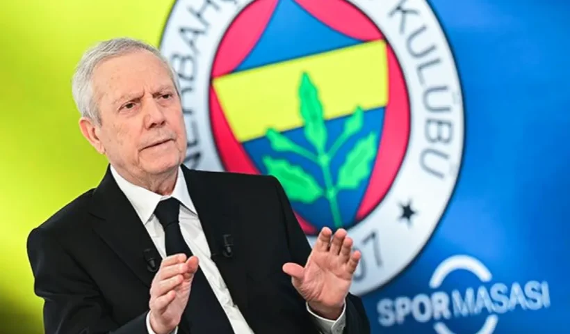 Aziz Yıldırım con traje y corbata con un enorme escudo del Fenerbahçe de fondo