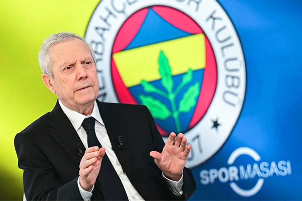 Aziz Yıldırım con traje y corbata con un enorme escudo del Fenerbahçe de fondo