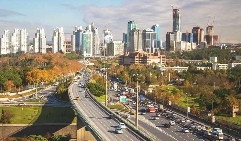 Traffic flowing along a major highway that runs through a landscaped area lined with numerous skyscrapers in the Levent business district of Istanbul