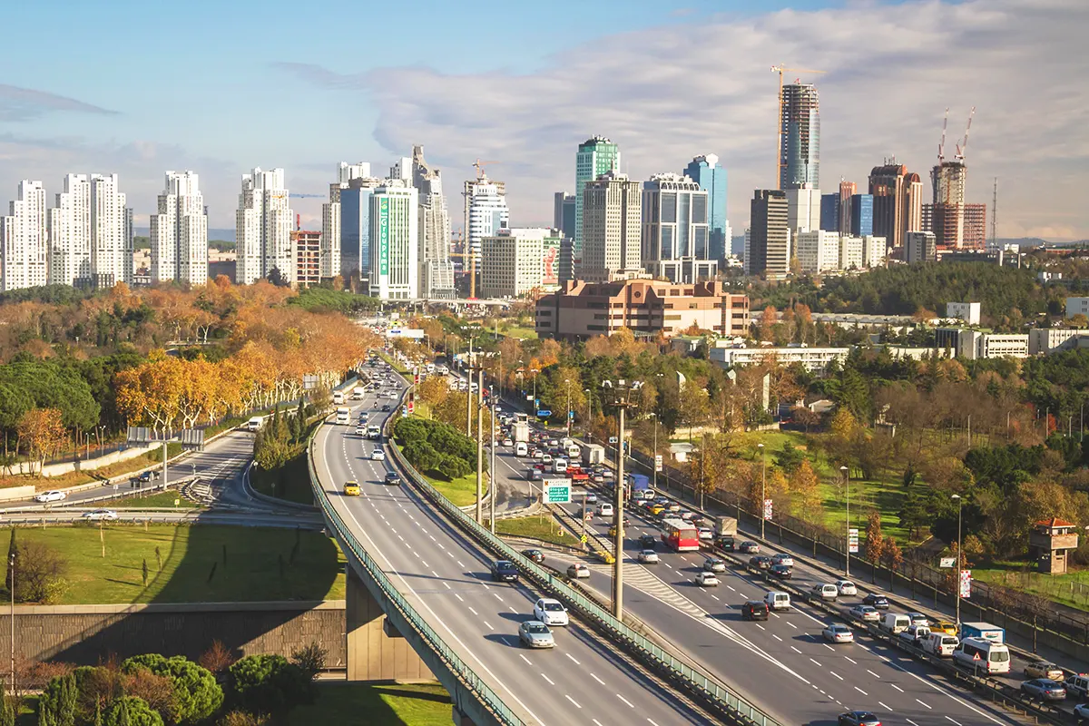 Traffic flowing along a major highway that runs through a landscaped area lined with numerous skyscrapers in the Levent business district of Istanbul