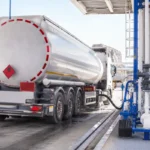 un camión cisterna siendo llenado de combustible en una refinería