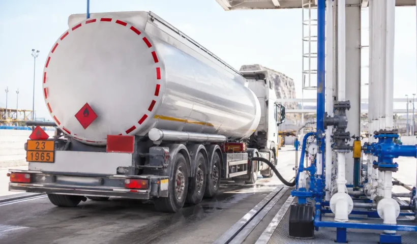 un camión cisterna siendo llenado de combustible en una refinería