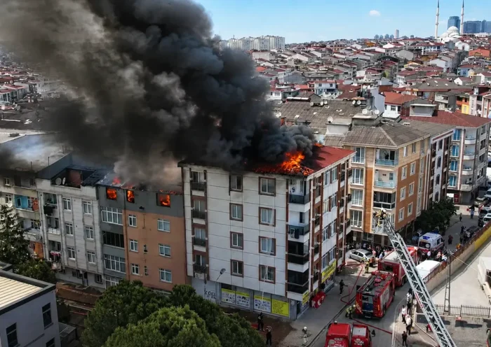 Flames and smoke billowing from several buildings in a residential block, with several fire engines in the vicinity