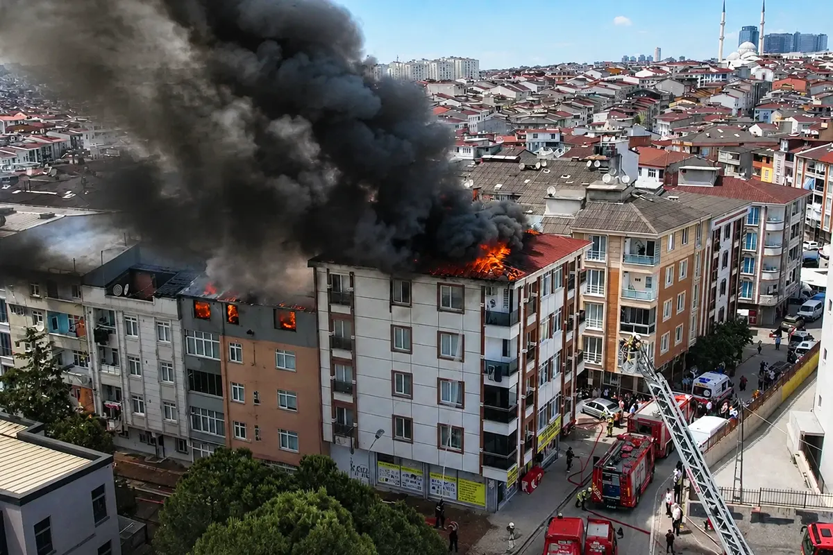 Flames and smoke billowing from several buildings in a residential block, with several fire engines in the vicinity