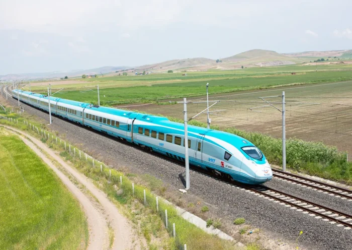 A high-speed train crosses a green plain in Turkey