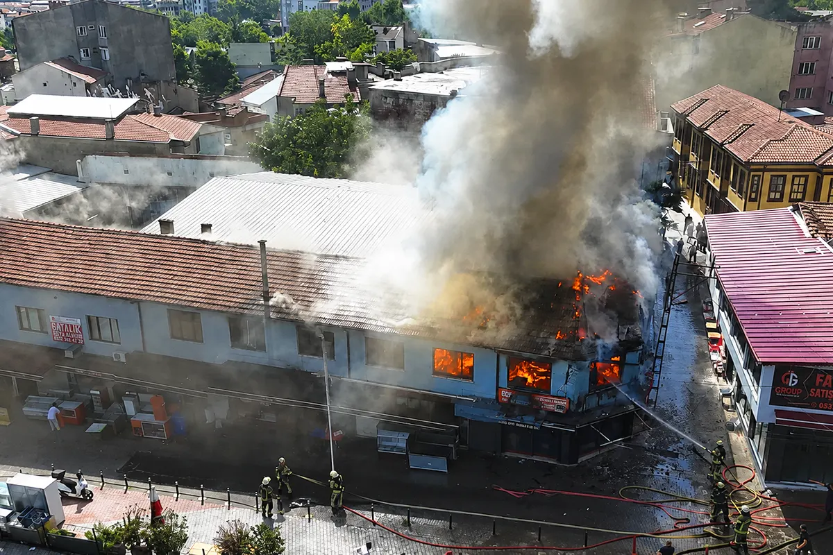 una gran columna de humo saliendo de un edificio en llamas en un bazar