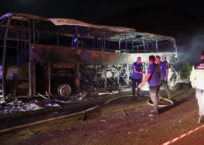 varios efectivos de emergencia durante la noche junto a los restos de un autobús totalmente calcinado