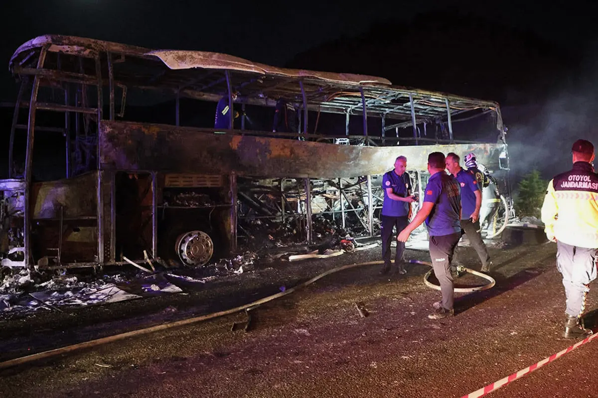 varios efectivos de emergencia durante la noche junto a los restos de un autobús totalmente calcinado