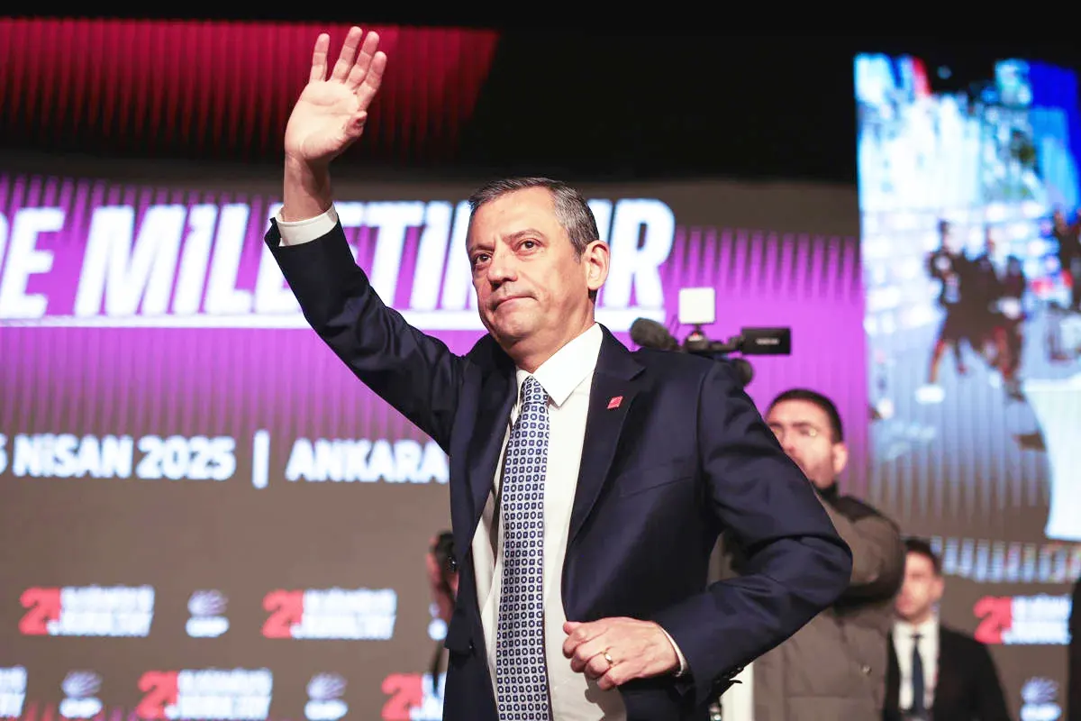Turkish politician Özgür Özel greets the crowd with a serious expression during a public event