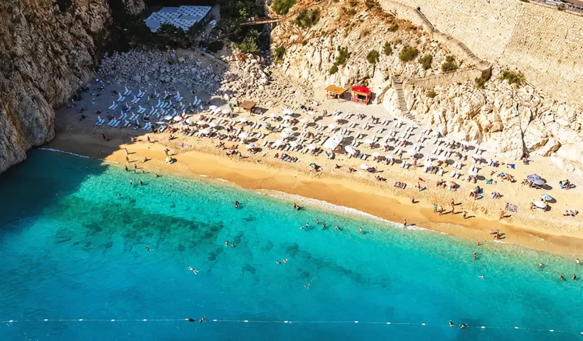 imagen aérea de la playa de Kaputaş en Antalya, en un estrecho acantilado y frente a un mar de aguas turquesas, llena de gente