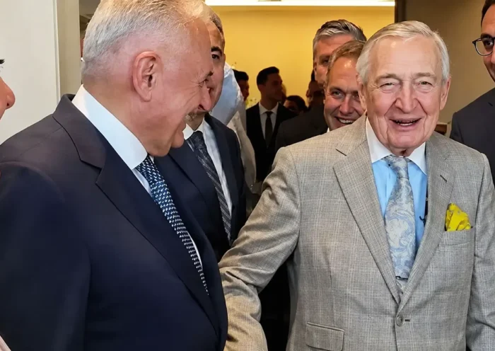 Turkish businessman Rahmi Koç is pictured with several people, including former Prime Minister Binali Yıldırım, as everyone present laughs