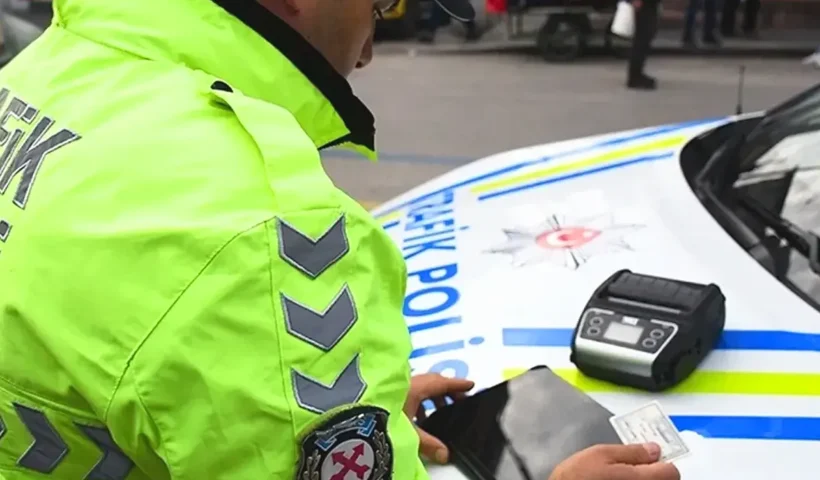 A Turkish traffic officer is examining some documents on the bonnet of a police car