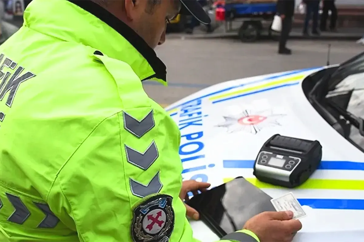 A Turkish traffic officer is examining some documents on the bonnet of a police car