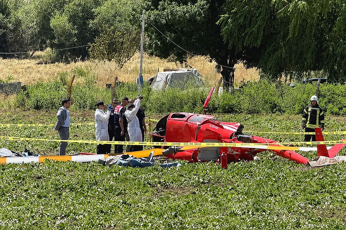 forenses, militares y equipos de emergencia rodean los restos de un helicóptero en un campo